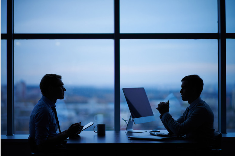 Two business advisors discussing risk in a blue lit office